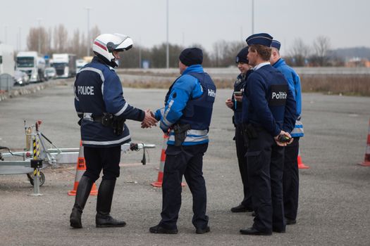 FRANCE, Neuville-en-Ferrain: Belgian police officers shake hands with French police officers as they check vehicles at the French-Belgian border, near Neuville-en-Ferrain, northern France, on March 22, 2016 , as security measures have been reinforced after a series of apparently coordinated explosions ripped through Brussels airport and a metro train on Tuesday, killing at least 26 people in the latest attacks to target Europe.