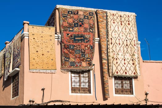 House with a carpets shop. Carpets displayed hanging from the roof. Bright blue sky. Medina of Marrakesh, Morocco.