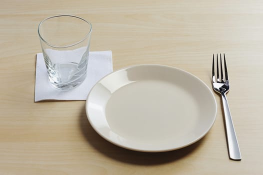 empty plate on wood table with glass and fork