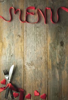 Valentine menu background made from red ribbon bow with cutlery and baubles 