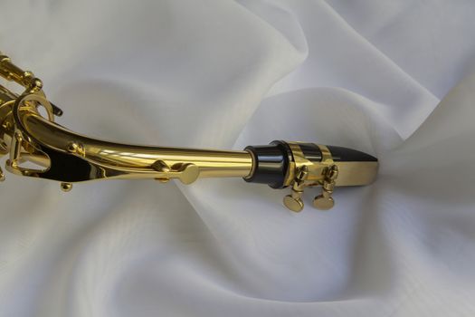 beautiful golden saxophone on delicate White silk background
