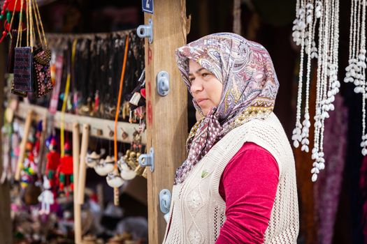 ASSOS, TURKEY – APRIL 23: Unidenified woman in head scarf selling trinkets and souvenirs during buildup to Anzac Day on April 23, 2012 in Assos, Turkey. 