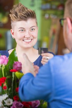 Cute female customer in flower shop using credit