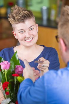 Smiling female customer in flower shop using credit