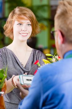 Smiling customer in a busy flower shop using electronic coupon