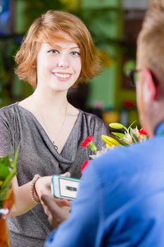 Teen customer in a busy flower shop using electronic coupon