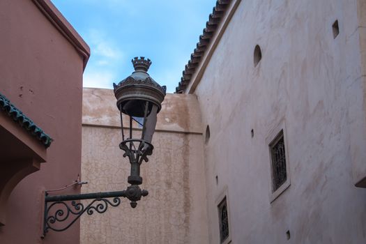 Early morning during dawn in the medina of Marrakesh. Traditional houses and a broken lantern. Blue sky with soft clouds.