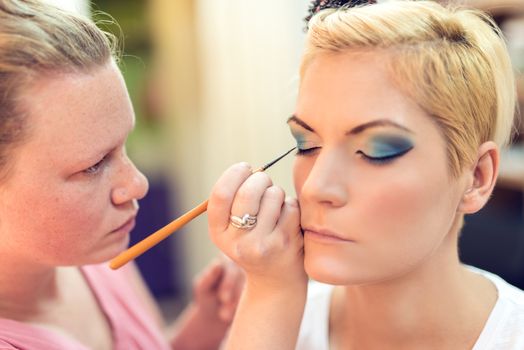 Make-up artist applying the eyeshadow to model.