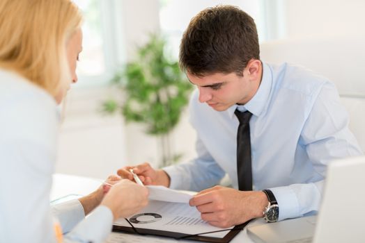 Businessman discussing and looking at document with female colleague in the office. Selective focus.