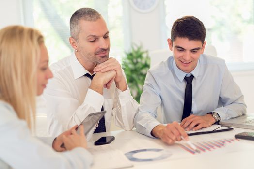 Business people having a meeting. Three business people looking at document and discussing in the office.