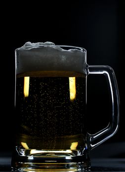 Glass brown beer with foam on black background