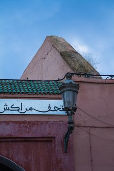 Colorful still life created by details of the houses and an old traditional lantern. White board with a notice in arabic script. Blue dawn sky.