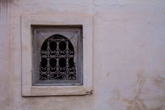 Still dark street during dawn of the medina in Marrakesh. Old light pink wall with a window with a wooden frame and decorative lattice.