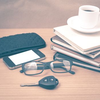 coffee and phone with stack of book,car key,eyeglasses and wallet on wood background vintage style