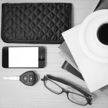 coffee and phone with stack of book,car key,eyeglasses and wallet on wood background black and white color