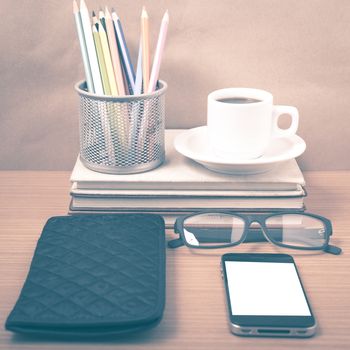 office desk : coffee with phone,stack of book,eyeglasses,wallet,color pencil box on wood background vintage style