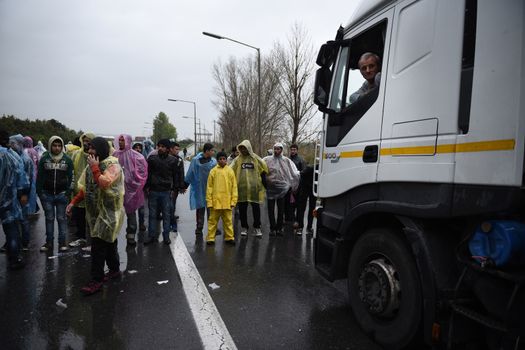 GREECE, Idomeni: A truck driver looks out from his cab at demonstrators blocking the road on March 23, 2016.Refugees and migrants blocked the main highway road near the northern Greek village of Idomeni at the Greek-Macedonian border, cutting off traffic between Greece and Macedonia, on March 23, 2016. People demonstrated demanding for the border to open, in order to continue their trip to northern Europe.