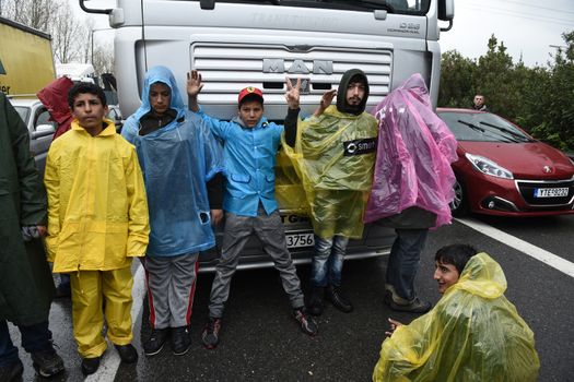 GREECE, Idomeni: Refugees stand in front of a truck on the road near the village of Idomeni on March 23, 2016.Refugees and migrants blocked the main highway road near the northern Greek village of Idomeni at the Greek-Macedonian border, cutting off traffic between Greece and Macedonia, on March 23, 2016. People demonstrated demanding for the border to open, in order to continue their trip to northern Europe.