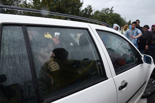 GREECE, Idomeni: A woman looks out from a car as migrants block the road on March 23, 2016.Refugees and migrants blocked the main highway road near the northern Greek village of Idomeni at the Greek-Macedonian border, cutting off traffic between Greece and Macedonia, on March 23, 2016. People demonstrated demanding for the border to open, in order to continue their trip to northern Europe.
