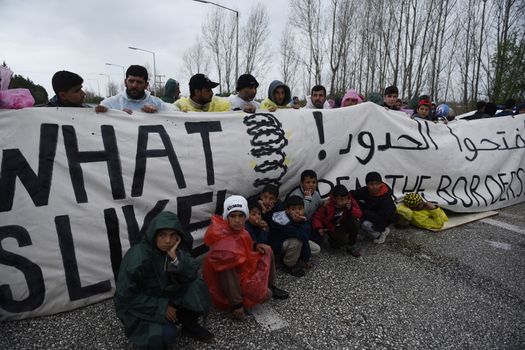 GREECE, Idomeni: Migrants hold a banner, blocking the road on March 23, 2016.Refugees and migrants blocked the main highway road near the northern Greek village of Idomeni at the Greek-Macedonian border, cutting off traffic between Greece and Macedonia, on March 23, 2016. People demonstrated demanding for the border to open, in order to continue their trip to northern Europe.