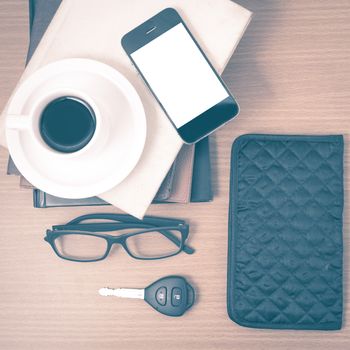 coffee and phone with stack of book,car key,eyeglasses and wallet on wood background vintage style