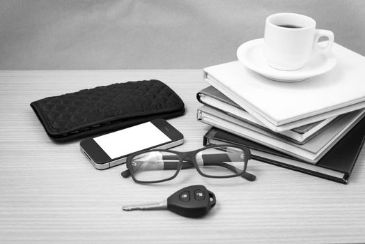 coffee and phone with stack of book,car key,eyeglasses and wallet on wood background black and white color