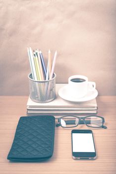office desk : coffee with phone,stack of book,eyeglasses,wallet,color pencil box on wood background vintage style