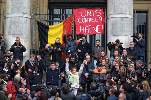 BELGIUM, Brussels: People hold a Belgian flag as they gather to pay tribute to the victims of the Brussels airport and metro bombings, on the Place de la Bourse in central Brussels, on March 23, 2016, a day after the triple blasts killed at least 31 people and left around 250 injured. World leaders united in condemning the carnage in Brussels and vowed to combat terrorism, after Islamic State bombers killed around 35 people in a strike at the symbolic heart of the EU.