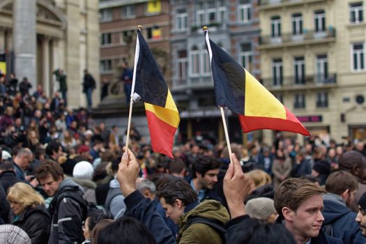 BELGIUM, Brussels: People hold a Belgian flags as they gather to pay tribute to the victims of the Brussels airport and metro bombings, on the Place de la Bourse in central Brussels, on March 23, 2016, a day after the triple blasts killed at least 31 people and left around 250 injured. World leaders united in condemning the carnage in Brussels and vowed to combat terrorism, after Islamic State bombers killed around 35 people in a strike at the symbolic heart of the EU.