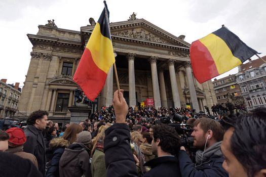 BELGIUM, Brussels: People hold a Belgian flags as they gather to pay tribute to the victims of the Brussels airport and metro bombings, on the Place de la Bourse in central Brussels, on March 23, 2016, a day after the triple blasts killed at least 31 people and left around 250 injured. World leaders united in condemning the carnage in Brussels and vowed to combat terrorism, after Islamic State bombers killed around 35 people in a strike at the symbolic heart of the EU.