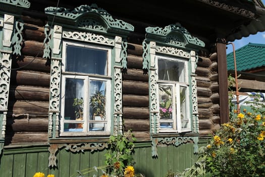 Window decorated with wood carvings on  log wall farmhouse