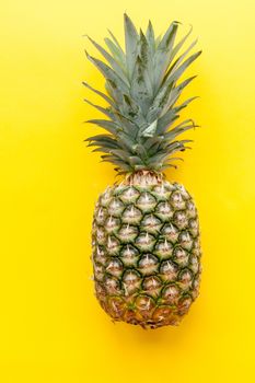 Natural and complete pineapple on a solid yellow background and flat