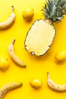 Natural and complete pineapple, bananas and lemons on a yellow background and flat