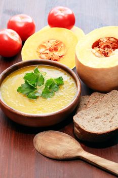 Nice wooden bowl with pumpkin soup near vegetables