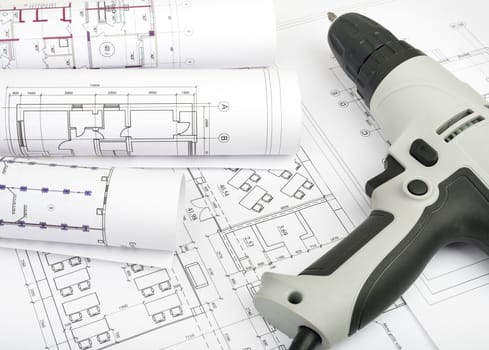 Architecture plan and rolls of blueprints with electric screwdriver. Building concept