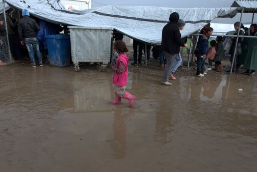 GREECE, Idomeni: One girl walks in mud as thousands of migrants are stranded in a makeshift camp for migrants and refugees at the Greek-Macedonian border near the village of Idomeni on March 23, 2016. The UN refugee agency harshly criticized an EU-Turkey deal on curbing the influx of migrants to Greece, saying reception centers had become detention facilities, and suspended some activities in the country. The EU and Ankara struck a deal aiming to cut off the sea crossing from Turkey to the Greek islands that enabled 850,000 people to pour into Europe last year, many of them fleeing the brutal war in Syria.