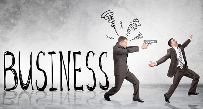 Businessman shooting  another man with word business on grey wall background
