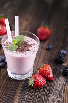 Tasty strawberry shake on wooden table with fruits