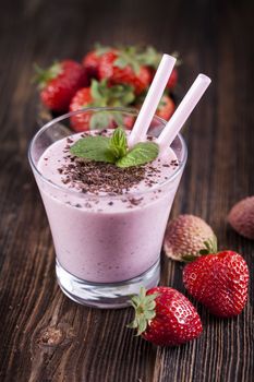 Tasty strawberry shake on wooden table with fruits