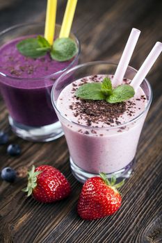 Tasty strawberry and blueberry shake on wooden table with fruits