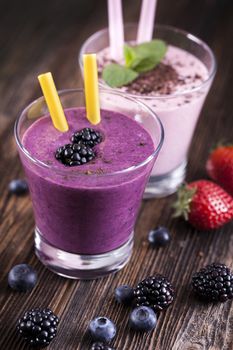 Tasty strawberry and blueberry shake on wooden table with fruits