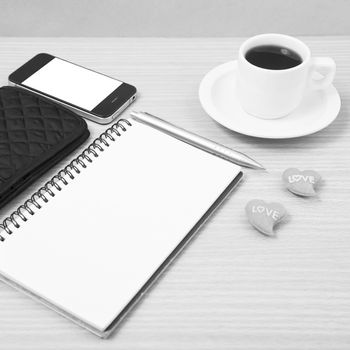 working table : coffee with phone,notepad,wallet and red heart on wood background black and white color