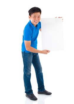 Asian businessman holding a blank card board with copy space, standing on plain background.