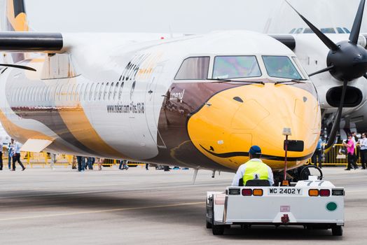 Singapore - February 17, 2016: Front of a Bombardier Q400 NextGen in Nok Air livery being pushed into position during Singapore Airshow at Changi Exhibition Centre in Singapore.