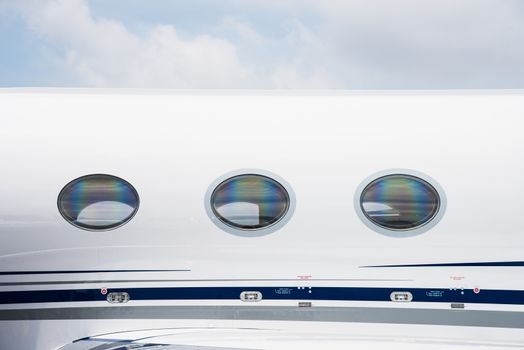 Windows and fuselage detail of white business jet aircraft.