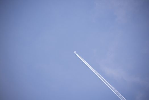 jet and its vapour trails in a cloudy blue sky