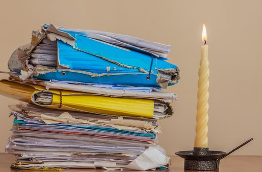 analyze a stack of documents and folders un the light of  a candle
