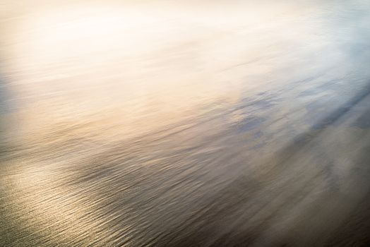 Reflection of the sky and sunlight in the wet sand of the sea