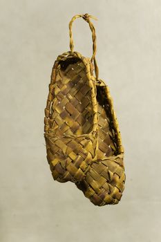 Old Russian sandals made of bark on a grey background