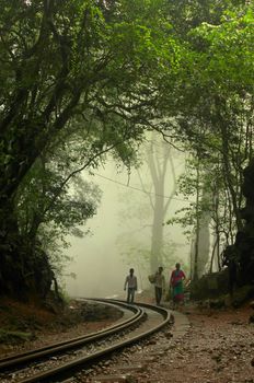 People walk up a railway track on a hillstation in India during early morning hours